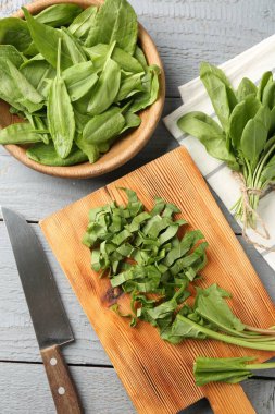 Gri ahşap masada taze kuş yaprakları ve bıçak kes, düz uzan.