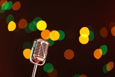Karanlık arka planda bulanık ışıkları olan klasik mikrofon, mesaj için yer. Müzik ekipmanları