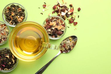 Cam fincanda nefis bitki çayı ve açık yeşil arka planda kuru yapraklar.