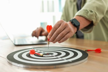 Dart tahtası olan bir adam, dizüstü bilgisayarda çalışırken, yakın plan.