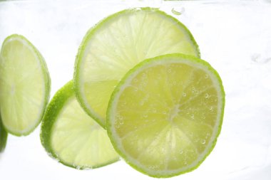 Soda tazeleniyor. Beyaz arka planda limon dilimleri var. Yakın plan.