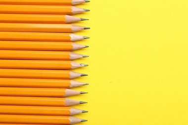 Sarı arka planda keskin grafit kalemler, düz. Metin için boşluk