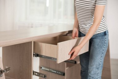 Mobilya montajı. Evde çekmeceyle çalışan bir kadın, yakın plan.