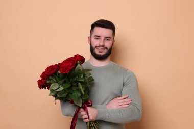 Bej arka planda kırmızı gül buketi olan mutlu adam.