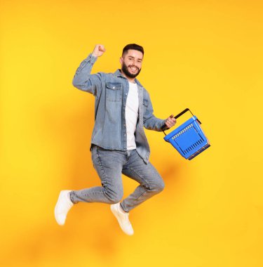 Turuncu arka planda boş alışveriş sepeti olan bir adam.