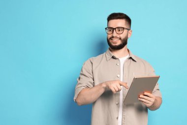 Açık mavi arkaplanda tablet kullanan adam, metin için boşluk