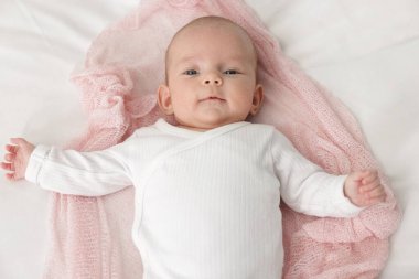 Evdeki yatakta uzanmış şirin küçük bebek, üst manzara.
