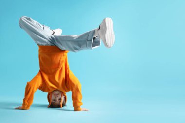 Açık mavi arka planda dans eden şık elbiseli çocuk, metin için yer var.