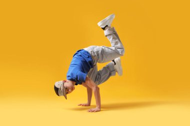 Şık giyinmiş çocuk turuncu arka planda dans ediyor.