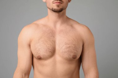 Açık gri arka planda kıllı göğüslü genç adam, yakın plan. Epilasyon işlemi