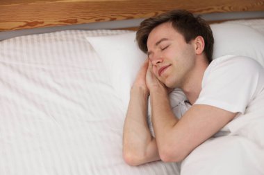 Genç adam yatağında uyuyor.