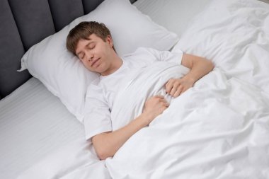 Genç adam yatağında uyuyor, yukarıda.