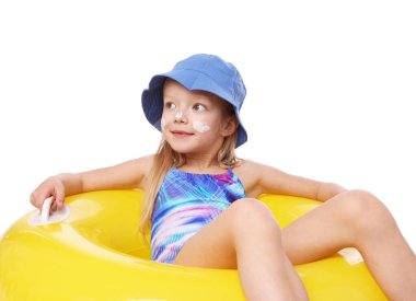 Cildinde güneş kremi ve beyaz arka planda şişme yüzük olan sevimli küçük bir kız.