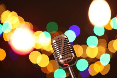 Karanlık arka planda bulanık ışıkları olan klasik mikrofon, mesaj için yer. Müzik ekipmanları