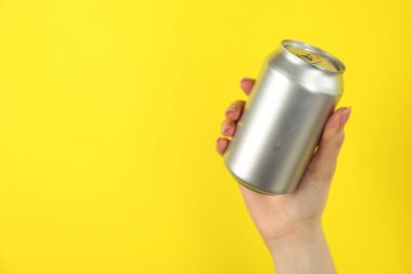 Sarı arka planda teneke kutusu olan kadın, yakın plan. Metin için boşluk