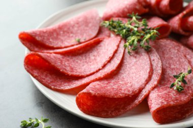 Gri masada servis edilen lezzetli sosis dilimleri, yakın plan.