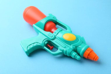 Açık mavi arkaplanda parlak plastik su tabancası, yakın plan.