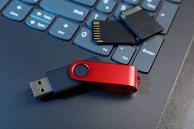 SD hafıza kartları, USB flaş bellek ve laptop koyu gri tabloda, yakın plan