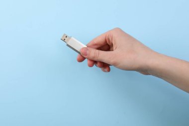 Flaş belleği açık mavi arka planda tutan kadın, yakın plan. Metin için boşluk