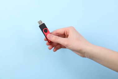 Flaş belleği açık mavi arkaplanda tutan kadın, yakın plan.