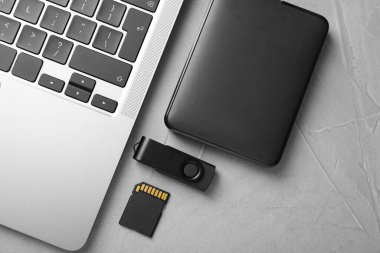 Flaş bellek, hafıza kartı, harici hard disk ve dizüstü bilgisayar açık gri tabloda, düz konum