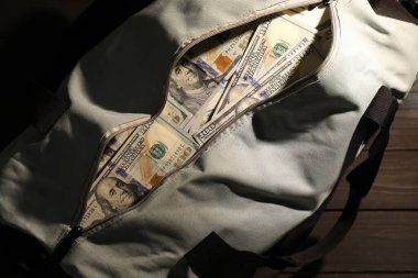 Tahta masanın üzerinde dolar banknotları olan çanta, üst manzara.