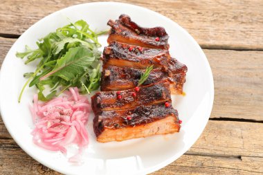 Lezzetli domuz pirzolası, roka ve soğan ahşap masada, yakın plan.