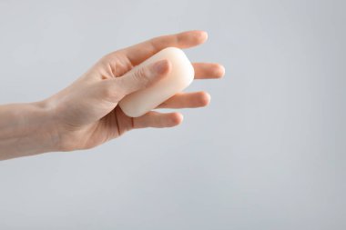 Açık gri arka planda sabun çubuğu olan kadın, yakın plan. Metin için boşluk