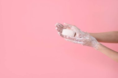 Açık pembe arka planda ellerini sabunla yıkayan kadın, yakın plan. Metin için boşluk