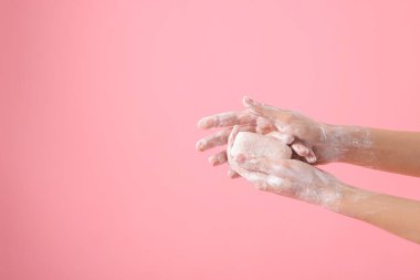 Açık pembe arka planda ellerini sabunla yıkayan kadın, yakın plan. Metin için boşluk