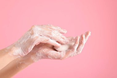 Açık pembe arka planda ellerini sabunla yıkayan kadın, yakın plan.