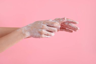 Açık pembe arka planda ellerini sabunla yıkayan kadın, yakın plan.