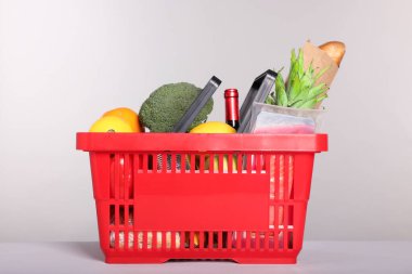 Gri arka planda farklı gıda ürünleri olan alışveriş sepeti.