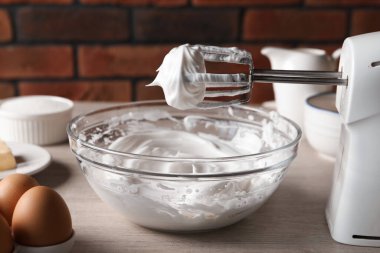 Çırpılmış çırpılmış çırpılmış krema ve çırpılmış kremayla el çırpıcısı tuğla duvara karşı, yakın plan.