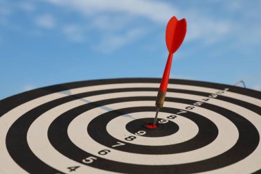 Hedef alınıyor. Mavi gökyüzüne karşı oklu dart tahtası, yakın plan.