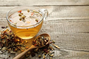 Lezzetli bitkisel çay ve kuru yapraklar ahşap masada, yakın plan. Metin için boşluk