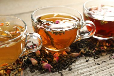 Tahta masada farklı bitki çayları ve kuru yapraklar, yakın plan.