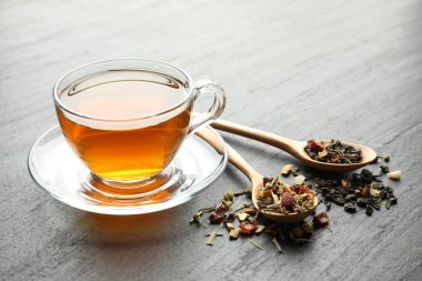 Lezzetli bitkisel çay ve kuru yapraklar siyah masada, yakın plan.