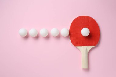 Masa tenisi raketi ve toplar pembe arka planda, düz yatıyordu.