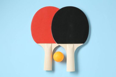 Masa tenisi raketleri ve top açık mavi arka planda, düz yatıyordu.