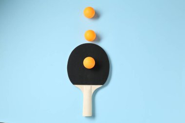 Masa tenisi raketi ve toplar açık mavi arkaplanda, düz yatıyordu