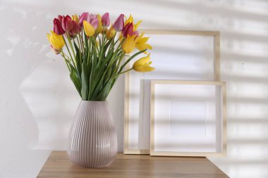 İçerideki ahşap masada güzel laleler ve çerçeveler.