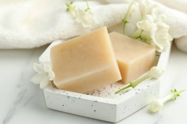 Sabun kalıpları, yasemin çiçekleri ve beyaz mermer masada havlu, yakın plan.