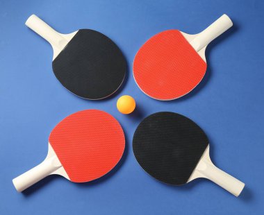 Masa tenisi raketleri ve top mavi arka planda, düz yatıyordu.