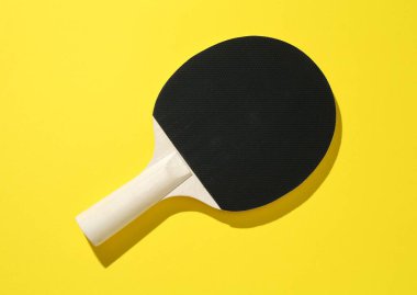 Sarı arka planda bir ping pong raketi, üst manzara.