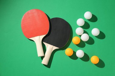 Yeşil arka planda pinpon raketleri ve topları düz yatıyordu.