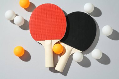 Masa tenisi raketleri ve topları arka planda, düz yatıyordu.