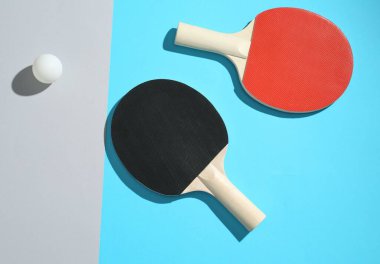 Renkli arka planda pinpon raketleri ve top, üst görünüm