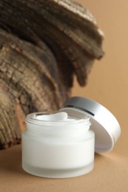 Bej arka planda bir kavanoz vücut kremi, yakın plan.