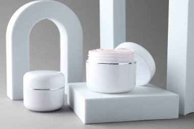 Açık gri arka planda kavanozlarda vücut kreminin şık sunumu, yakın plan